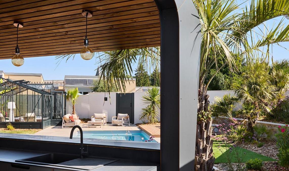 Angle extérieur du pool-house avec lames Nuances Ipé Silvadec au sol, cuisine d'extérieur et végétation méditerranéenne